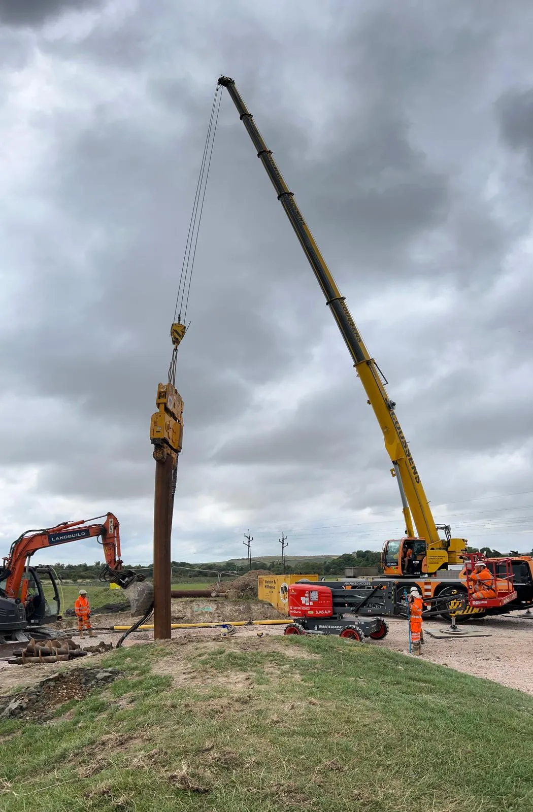 A crane is lifting a wooden pole into place.