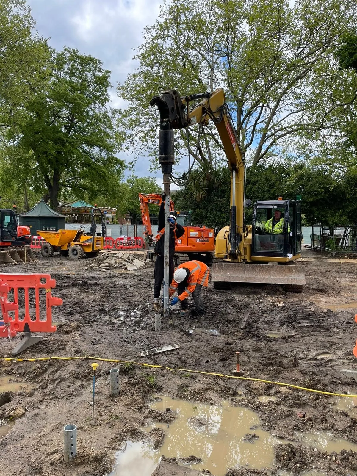 A construction site with construction equipment and trees.